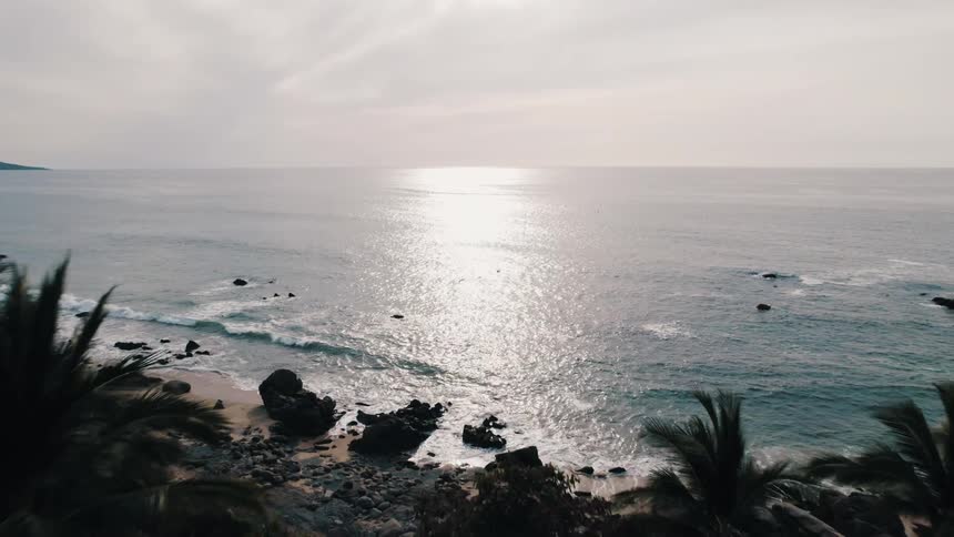 Ocean water stretches from beach near town to horizon and reflects sunlight