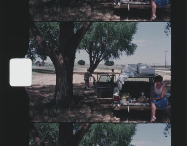 A family sitting outside next to their car