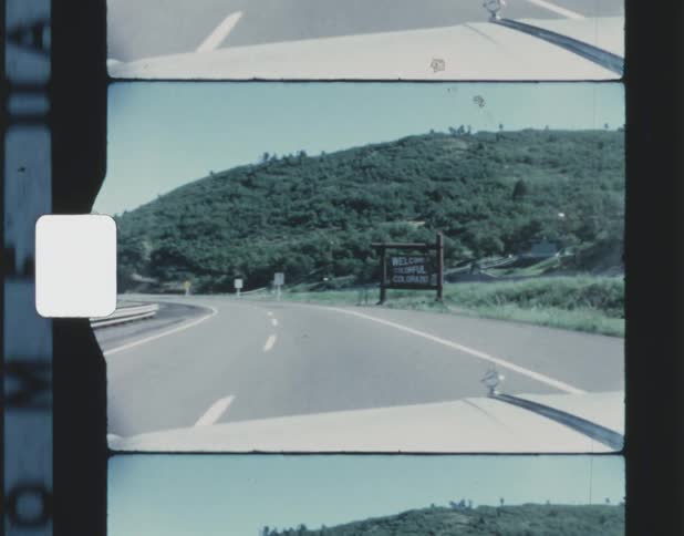 Traveling on a road by a welcome to colorful colorado sign and moving toward a forested mountain