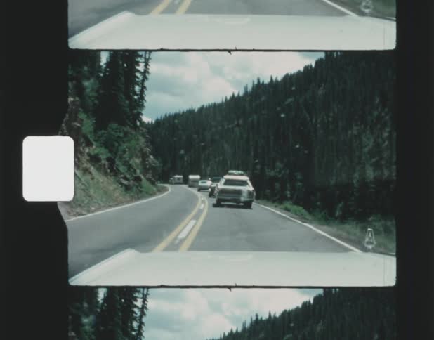 Cars are driving on a road in a wooded area