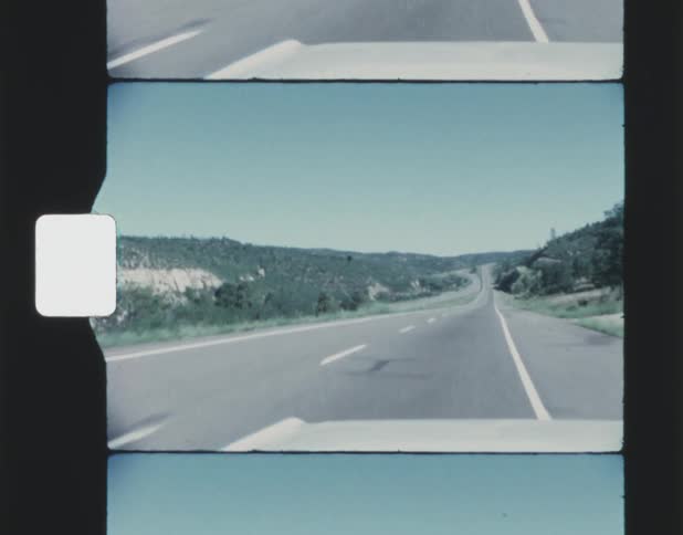 A two lane highway runs past a mountain range