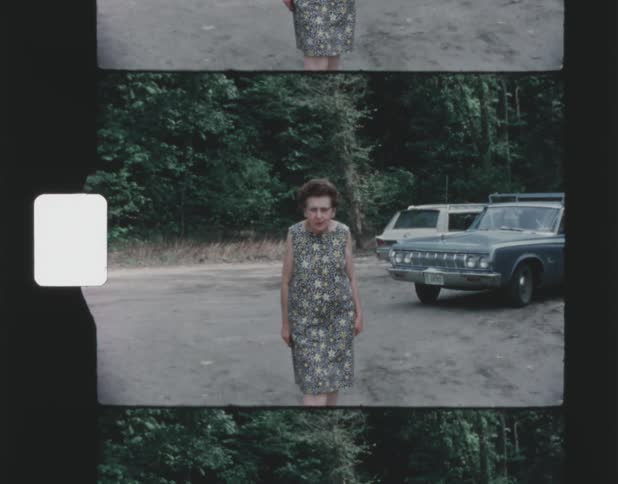 Old film footage of an elderly woman walking forwards and posing for a portrait