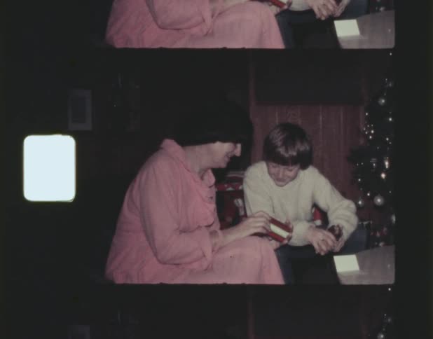 Old film footage of a boy watching his mother open a gift at christmas