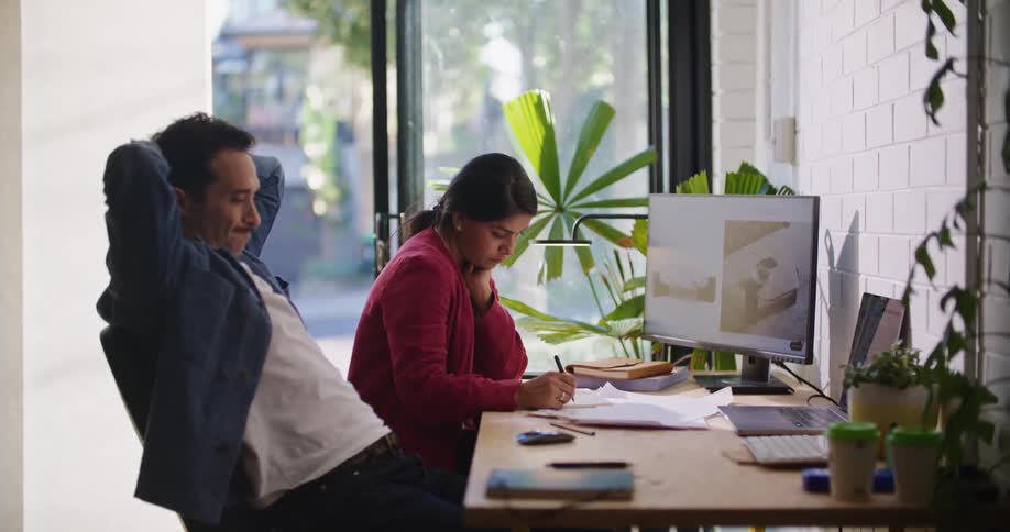 A man and woman both sit in a shared workspace and both looking up for inspiration