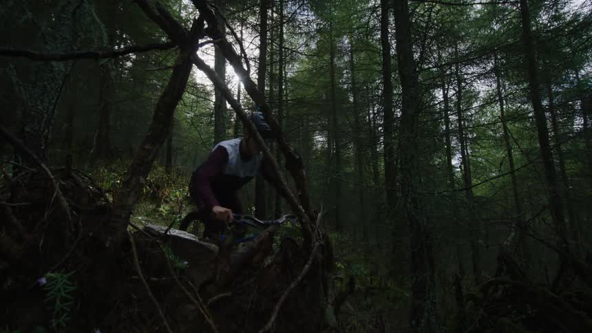 A man rides his bike downhill in the woods