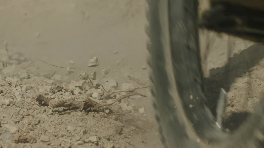 Bike tires bounce as they hit the ground as dirt and stones fly into the air