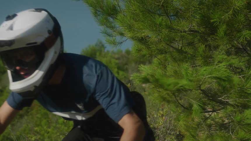 A man is riding his bike through a forest area