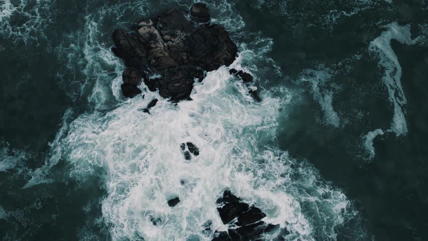 Large waves crash onto rocks along the shore