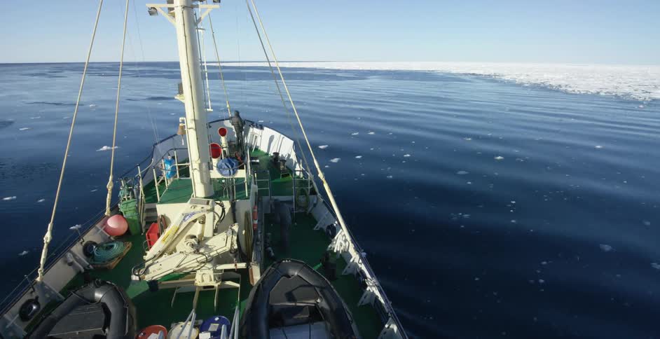 A man standing at the prow of a ship sailing in icy waters