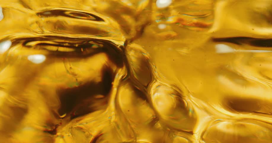 Amber liquid churns and flows as it reflects lights