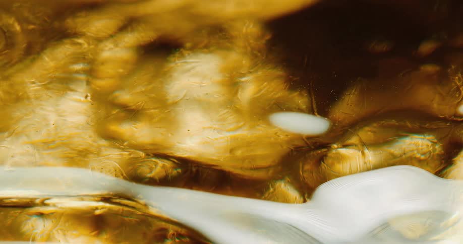 A gold liquid slowly moving around with a reflection on the surface