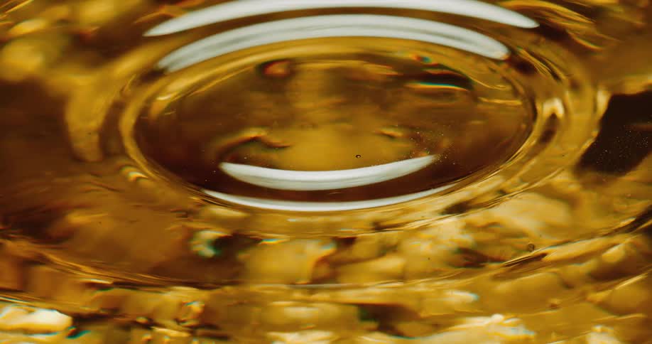 Droplet falls into golden water