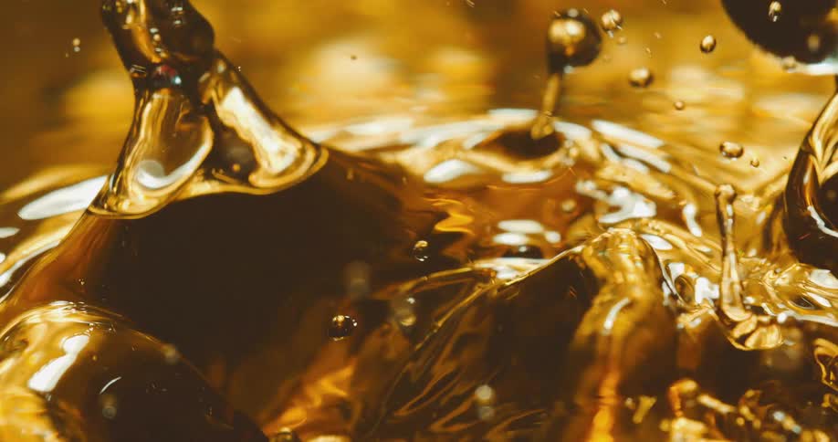Drops of gold liquid fall and splash