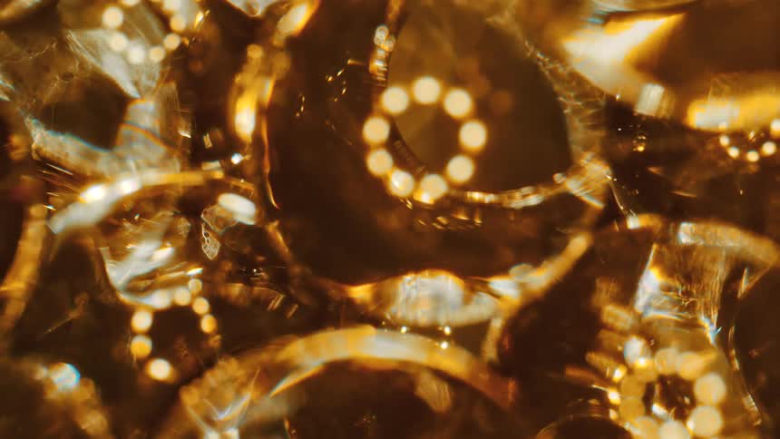 Clear spheres reflect rings of golden light as they fall and move