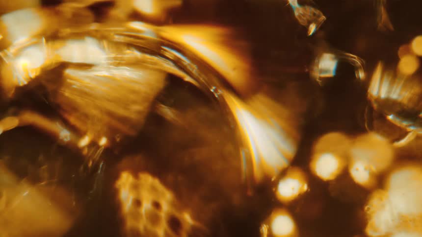 Multiple droplets of liquid are flowing and moving while refracting light