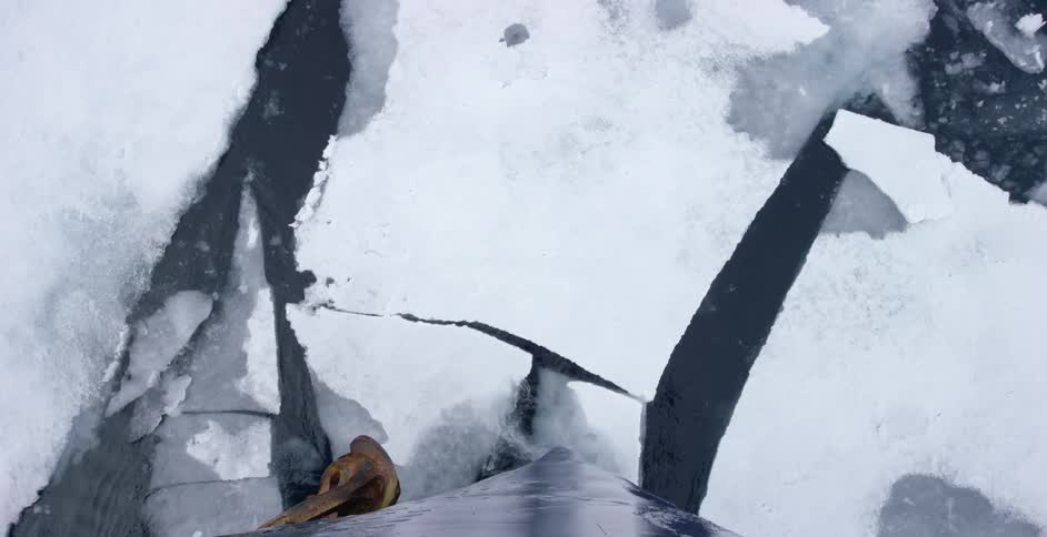 A boat smashes the ice in the water as it sails