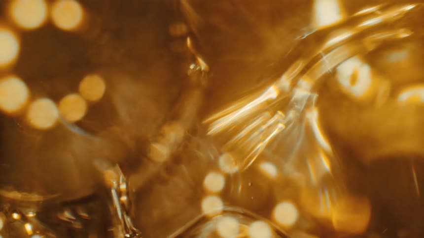 A close up of gold clear liquid moving around with bubbles in it
