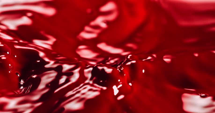 A red liquid being sloshed around creating waves and ripples in the liquid