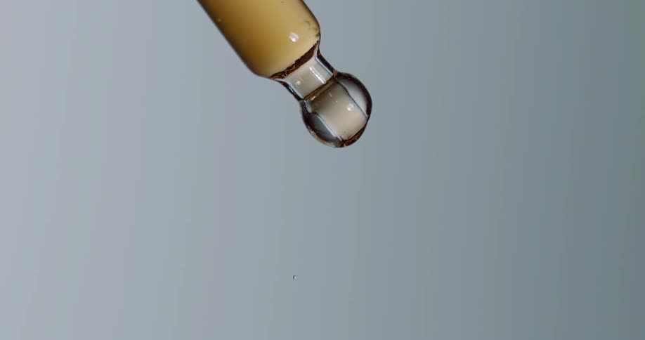 A close up of honey slowly dripping off a glass tool