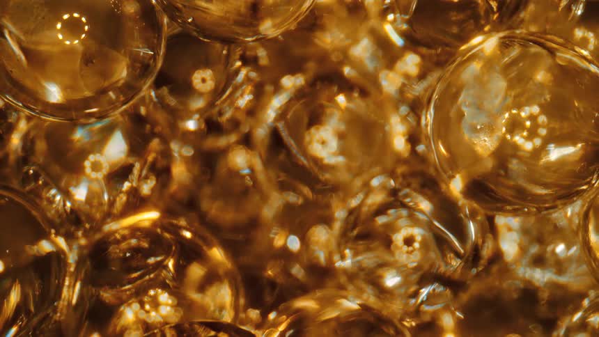 Clear spheres reflect rings of golden light as they jiggle and move