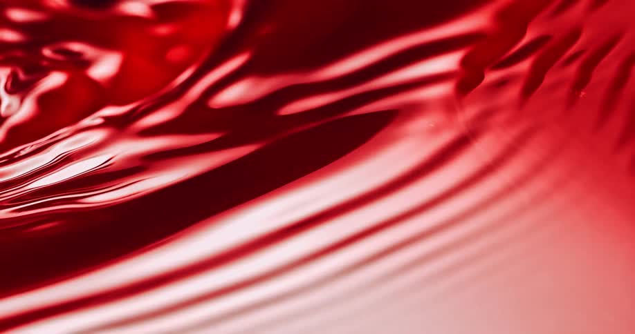 Small ripples flow across formerly smooth reflective crimson liquid