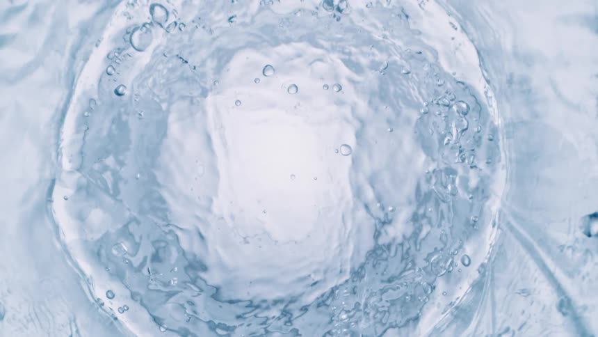 Clear liquid bubbles and fizzes as it swirls against translucent background