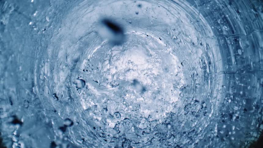 A circle rotates in the water like a whirlpool as bubbles rise among the rippling rings of water