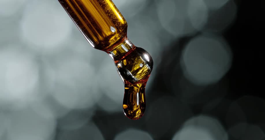 Gold liquid drips from the vial