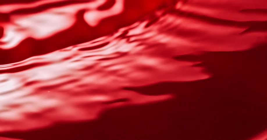 Ripples flow across red surface reflecting light
