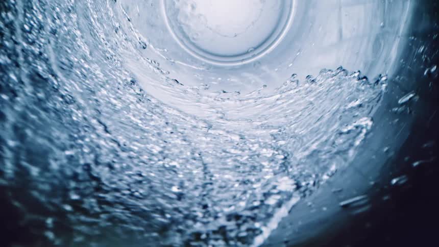 Water spiraling down a clear glass to the bottom