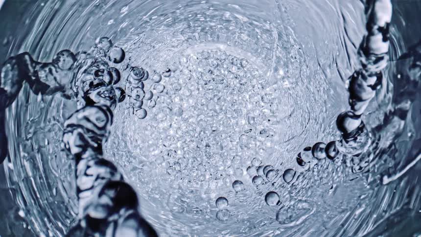Translucent streams emerge from clear lined container with spheres at the bottom