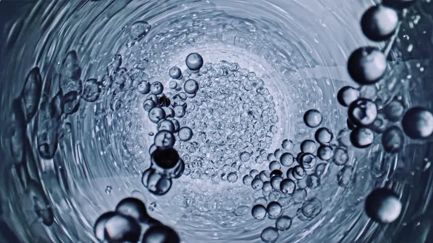 Globes in a clear tube rise towards the camera in slow motion
