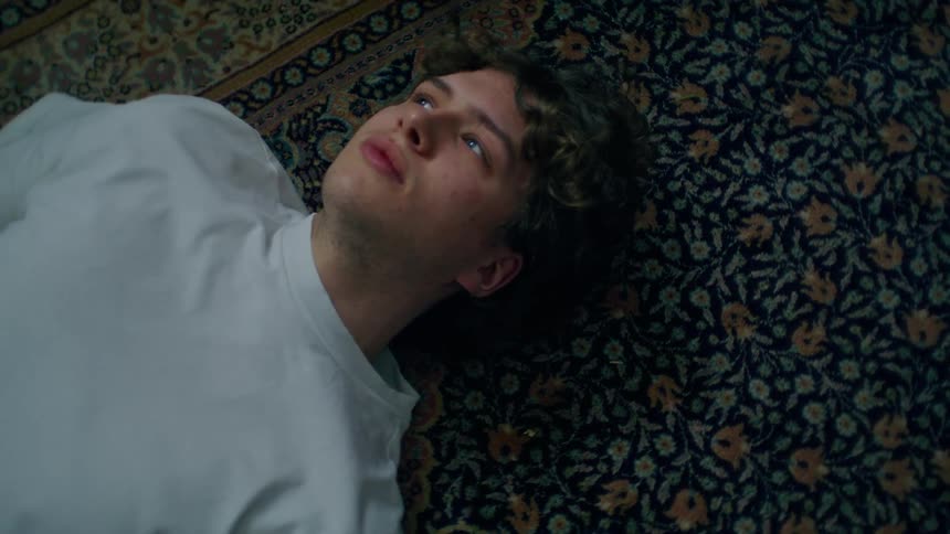 A man lies on a rug on the ground