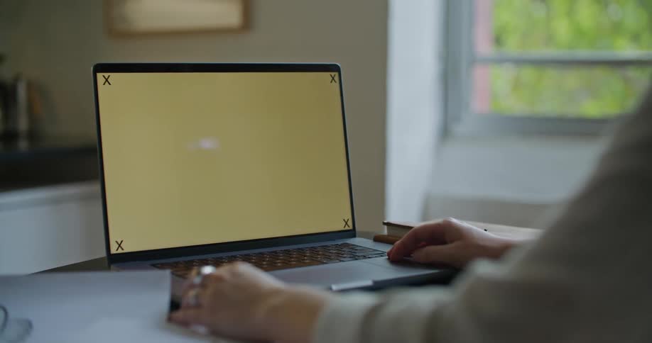 A laptop on a table with a person sitting in front of it using his finger to tap the mouse