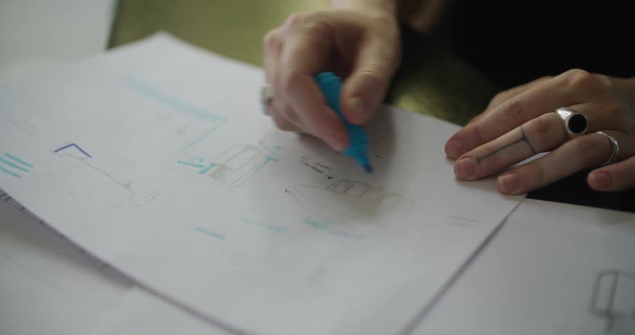 A person using a small blue highlighter to write on papers in front of her