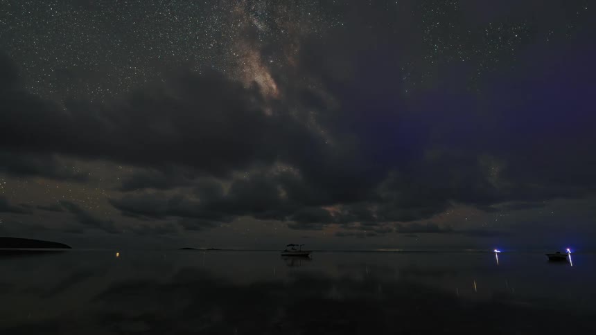 A time lapse shows clouds passing above boats on the water