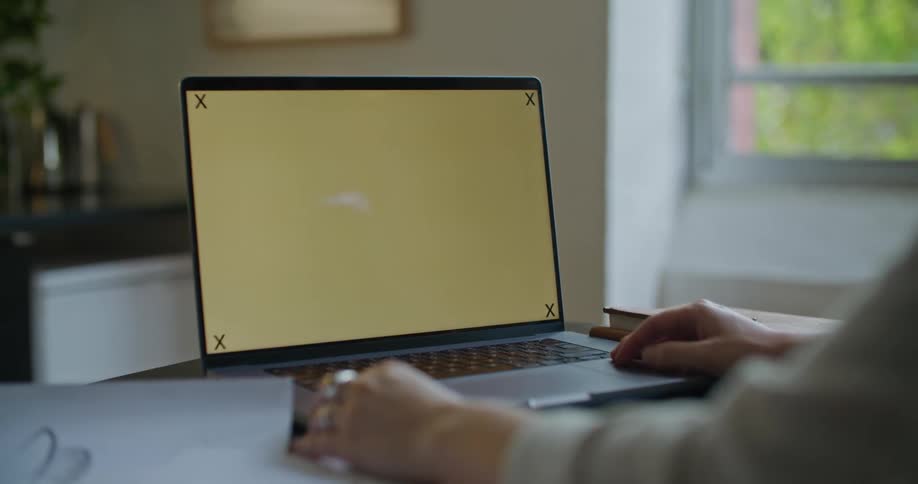 Woman with gray sweater uses laptop in the kitchen