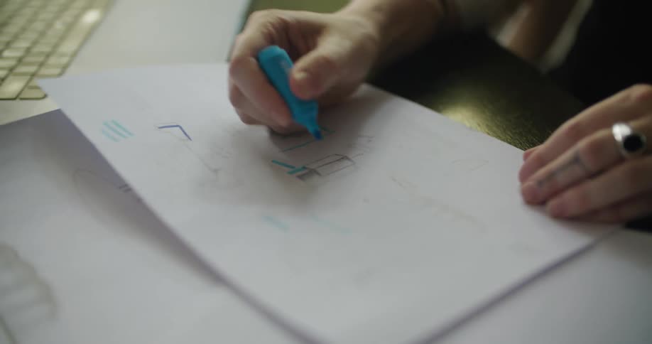 Woman draws lines on diagram on table with marker