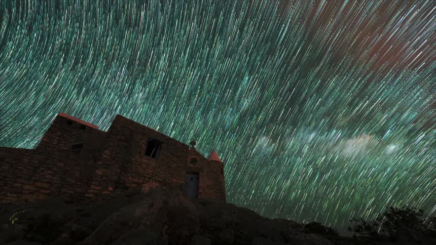 A time lapse of the stars in the sky behind an ancient castle