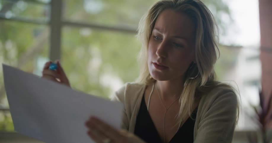 Woman sits in office reading and thinking