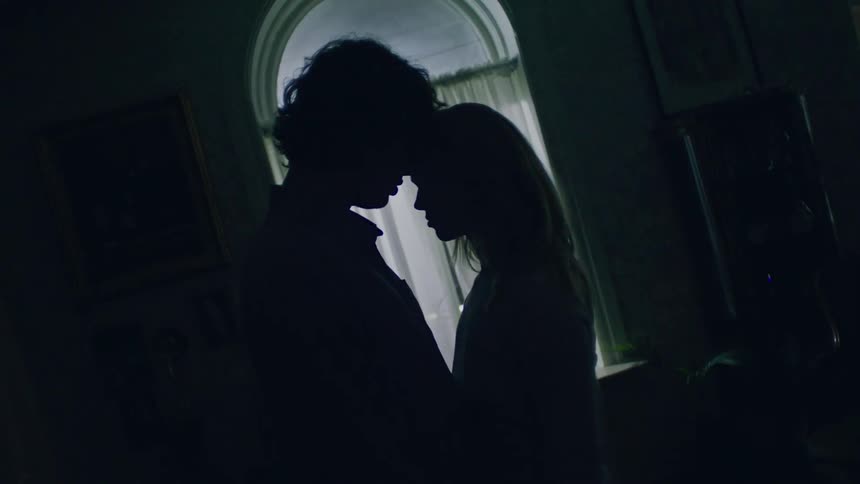 A couple stand in the living room with their foreheads touching