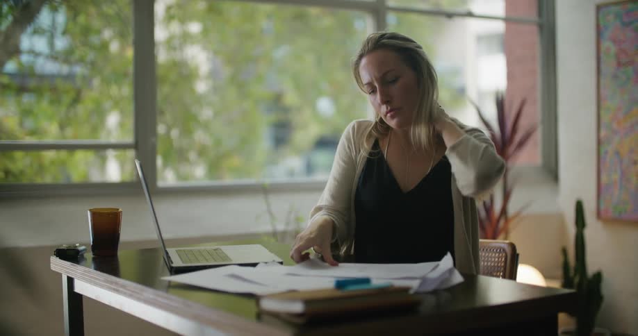 A woman looks through papers while sitting at her desk