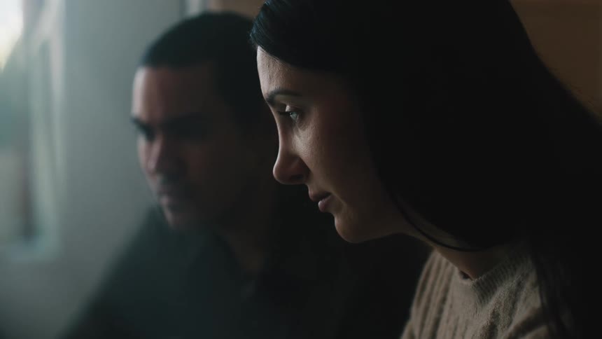 A woman and a man are sitting next to each other looking forward and occasionally speaking