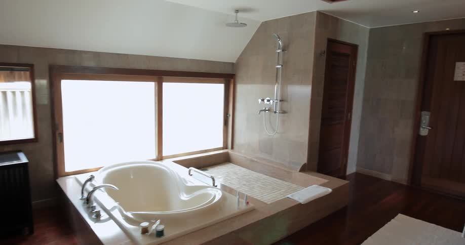 A bathroom has a small tub near windows