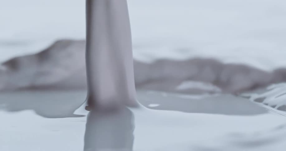 Light shines on pouring white liquid as it ripples and moves