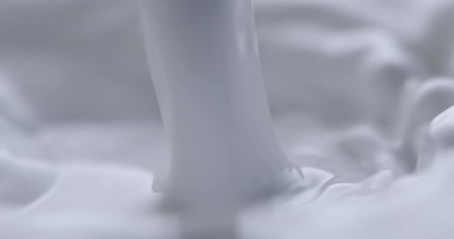 Light shines on pouring white liquid rippling and moving