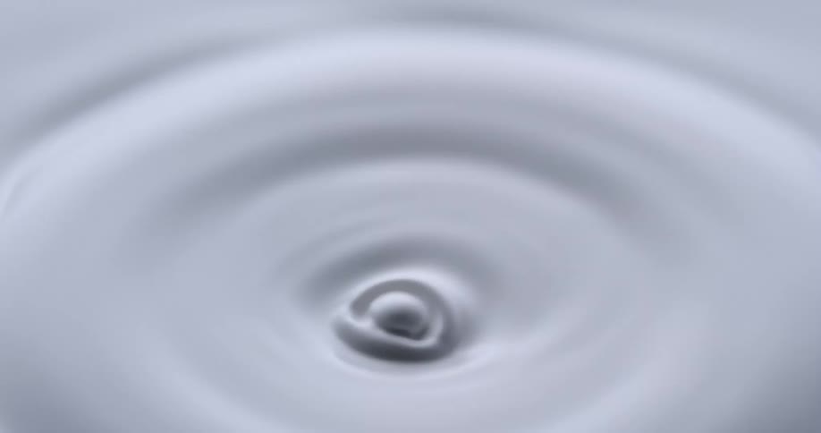 Slow motion extreme close up of a droplet of white liquid dropping into more white liquid and the resulting disturbance