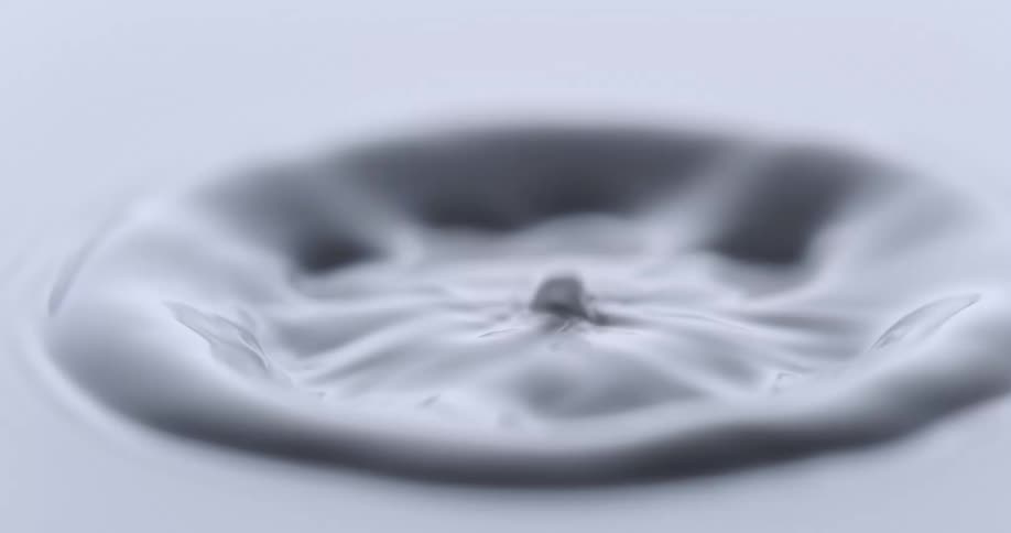 An orb falls into a white liquid and creates a circular ring splashing upwards and splashes back up from the center and more spheres fall in