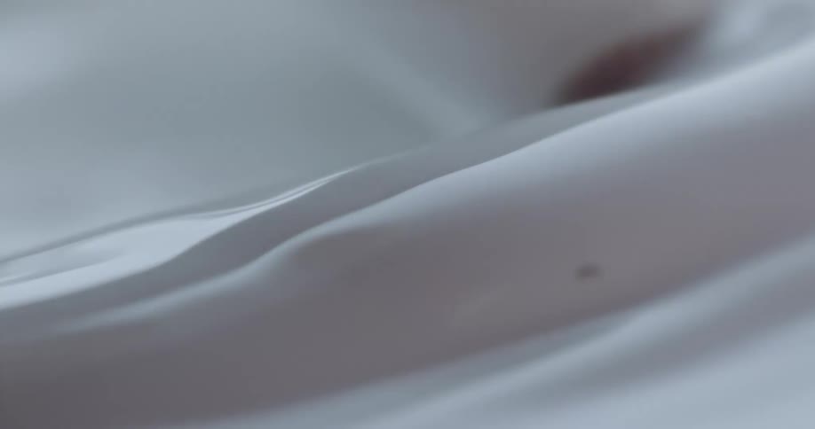 White liquid being poured and moved around creating ripples