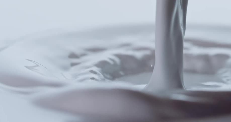 White milk being poured into itself splashing up and creating ripples